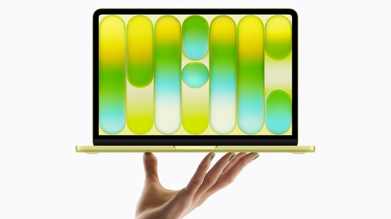 A hand holding up the MacBook Neo over a white background