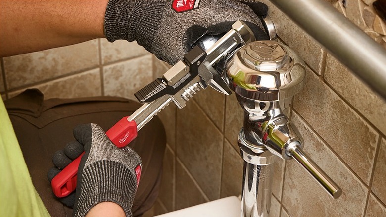 Man using a smooth jaw wrench for a plumbing task.