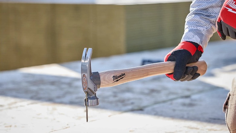 A nail fixed onto a framing hammer ready for an impact.