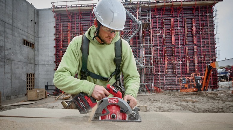 Worker using a circular saw on a construction site.