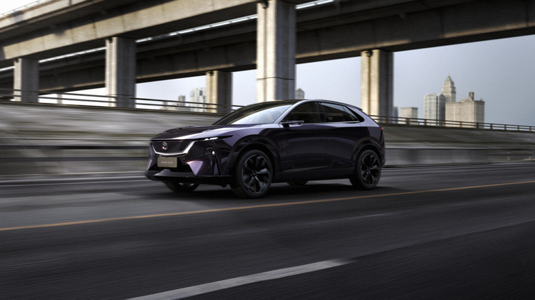 A purple 2026 Mazda EZ-60 EV moving on a highway while passing under an overhead bridge.