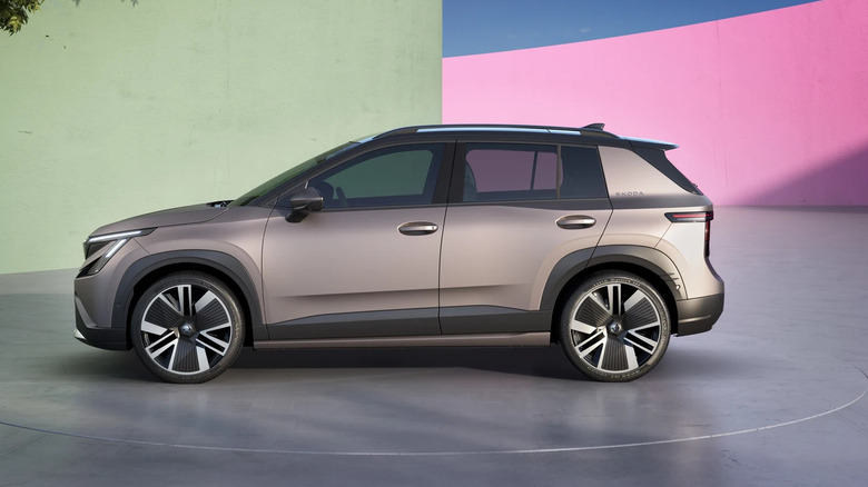 A silver-gray 2026 Skoda Epiq EV SUV pictured here in a left view, standing in a modern abstract environment.
