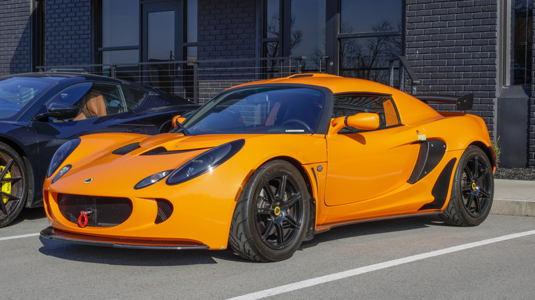 An orange 2006 Lotus Exige parked at a dealership
