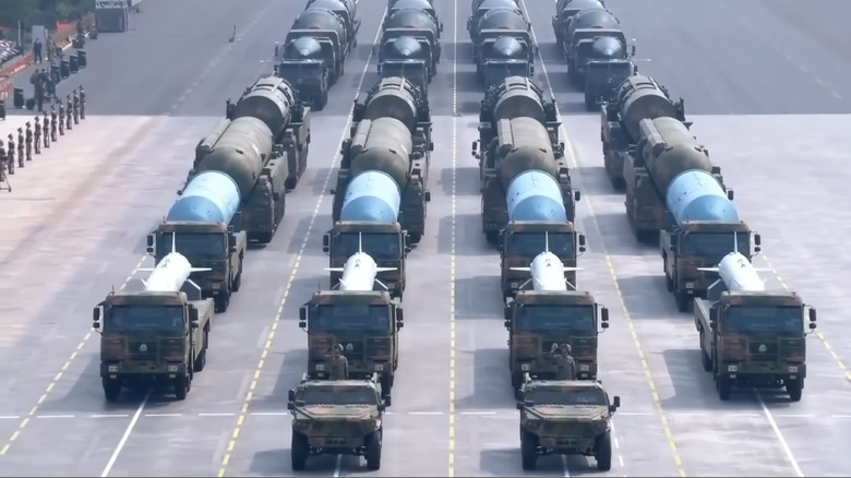 Several trucks with missile silos on top of them moving in formation.