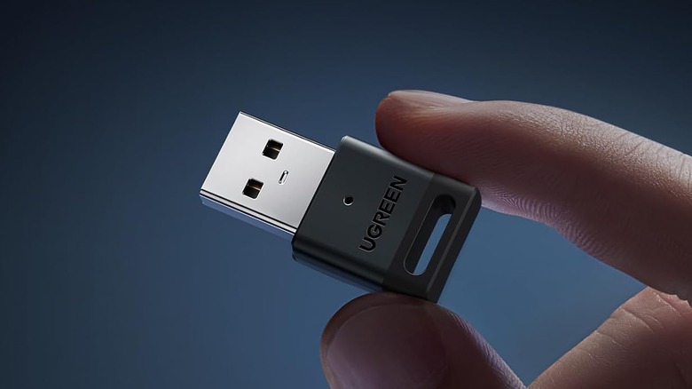 A person holding a tiny USB Bluetooth adapter.