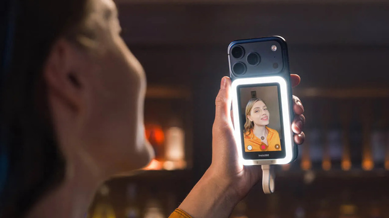 A person taking a selfie using an iPhone 17 Pro with the Insta360 Snap selfie screen installed
