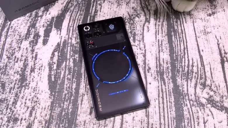RedMagic 11 Pro on a table, cat paw visible on a side.