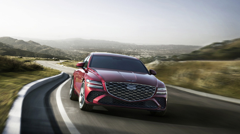 A 2025 Genesis G80 in vibrant red driving down a mountain road.
