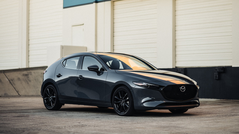 A gray 2025 Mazda3 hatchback parked in an industrial setting.