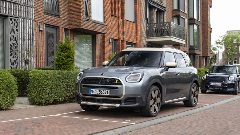 A silver 2025 MINI Cooper Countryman parked on a brick street in front of modern townhouses.