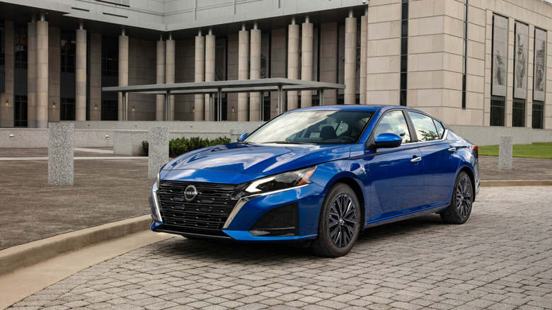 A blue 2025 Nissan Altima parked on a cobblestone driveway.