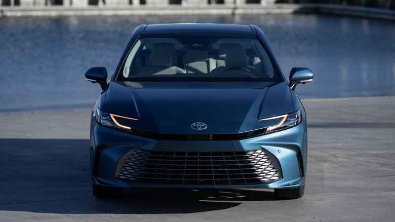 A front view of a blue 2025 Toyota Camry parked near the water.