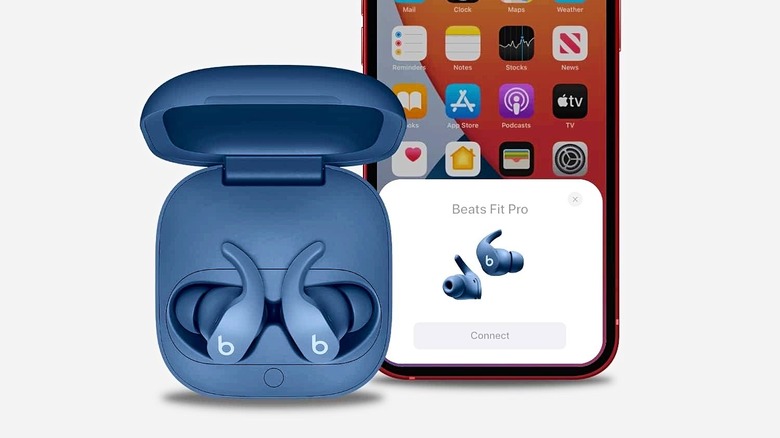 Blue Beats Fit Pro in their charging case next to a smartphone.