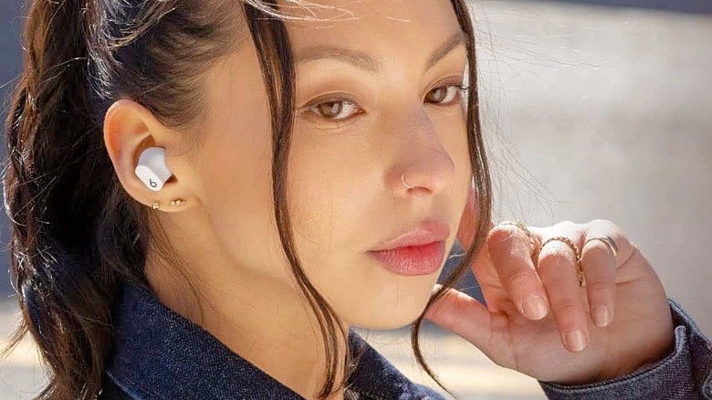 A woman wearing white Beats Studio Buds.