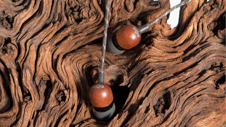 A pair of House of Marley Smile Jamaica earbuds against a tree bark background.