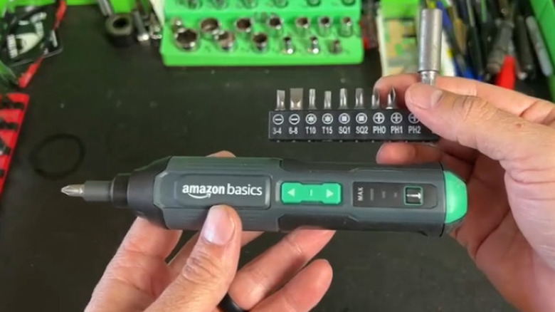 Person holding electric screwdriver over table