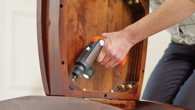 using electric screwdriver on underside of chair