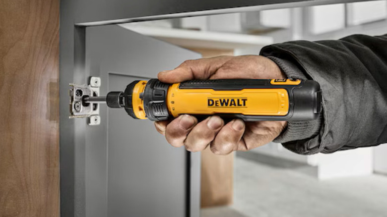 Person using electric screwdriver on cabinet door