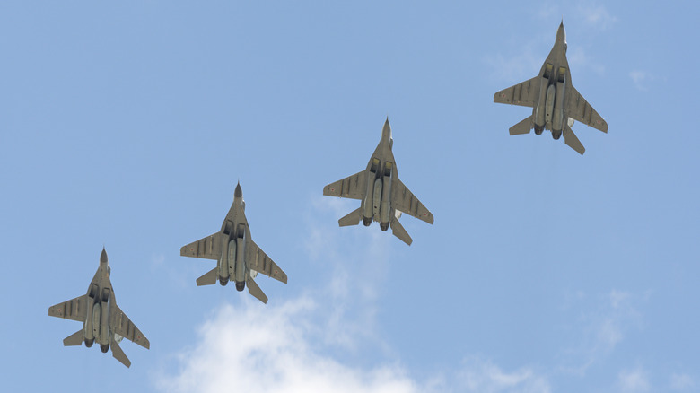 Four military MiG 25 aircraft performing a coordinated fly by over a public square in Russia