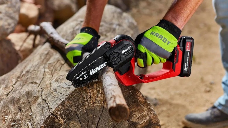 Person using Bauer cordless pruning saw to cut logs