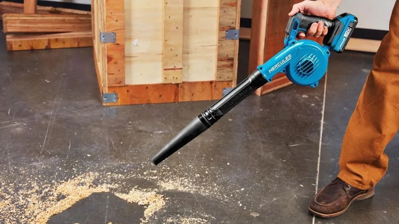 Person using Hercules Cordless Blower to clean sawdust