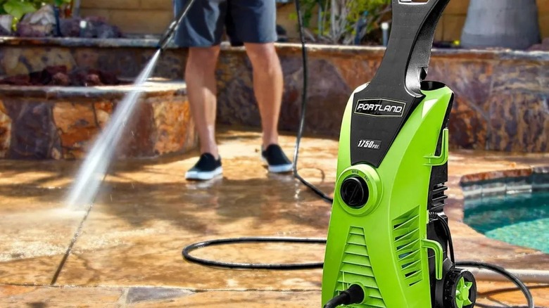 Person cleaning stone with Portland corded pressure washer