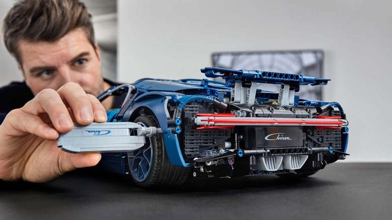 A man making adjustments to his completed LEGO Technic Bugatti Chiron.
