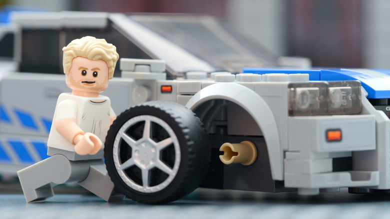 Lego minifigure changing the wheel on his Nissan Skyline GT-R.