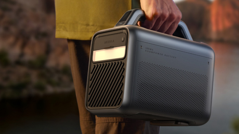 A man carrying the Anker Nebula Mars 3 by its carry handle.