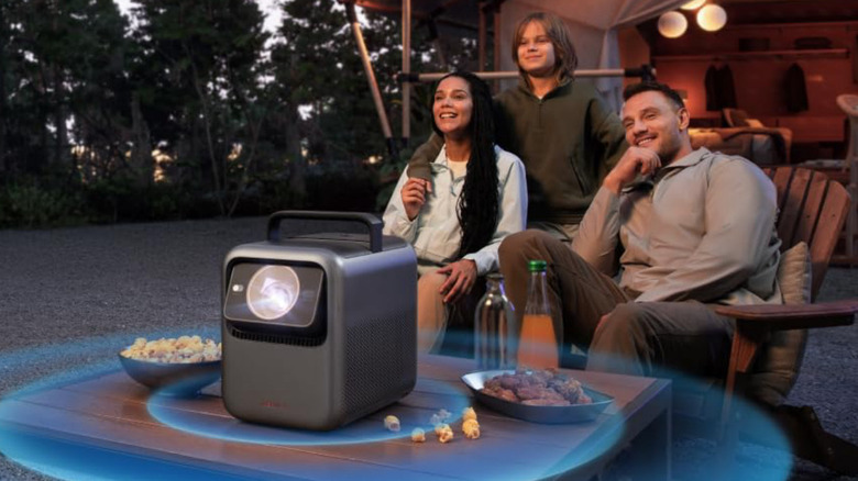 A family using the Anker Nebula X1 to watch a movie while camping.