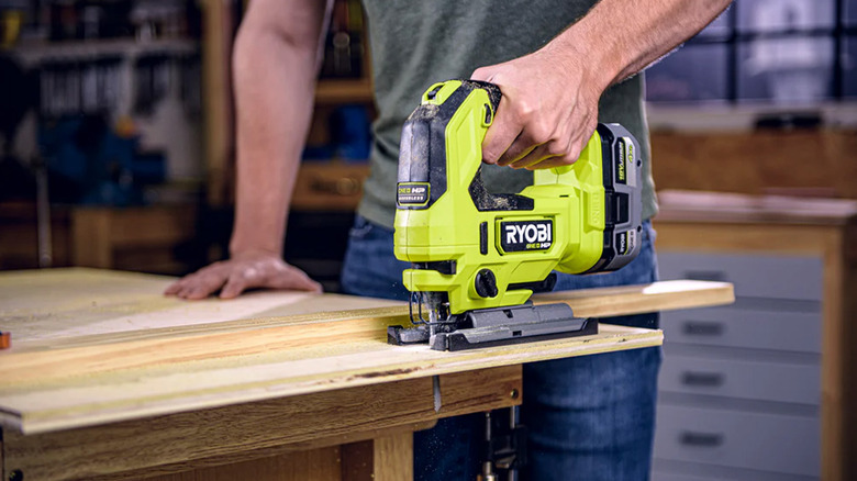 A man using a Ryobi jigsaw to cut a piece of wood