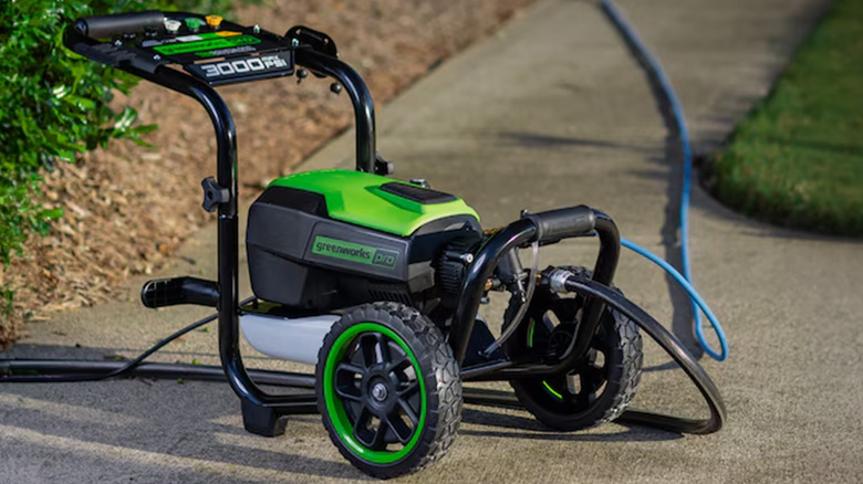 A Greenworks brand power washer at the end of a recently power washed sidewalk