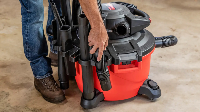 A man putting the hose of a Craftsman shop vac back in its spot
