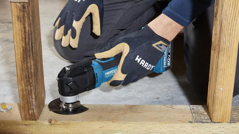 A man using a Hercules oscillating multitool on a piece of framing wood