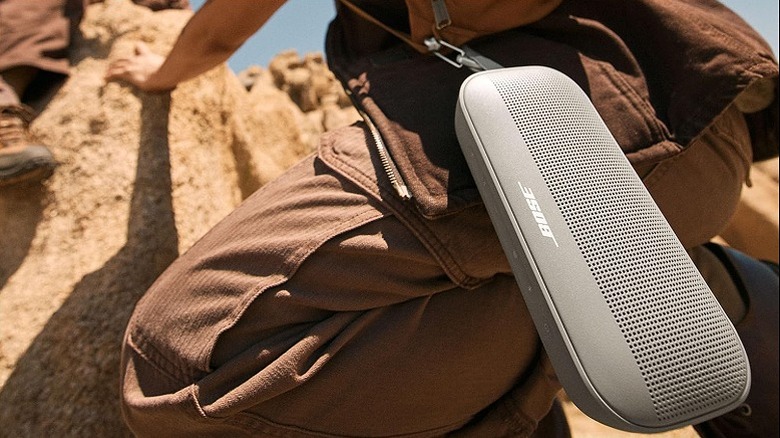Bose speaker hanging via a trap while a person climbs the rock.
