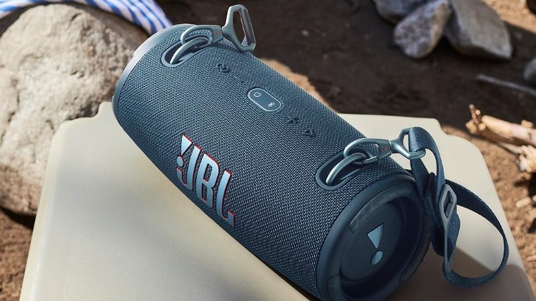 JBL speaker placed on a table alongside rocks and stones.