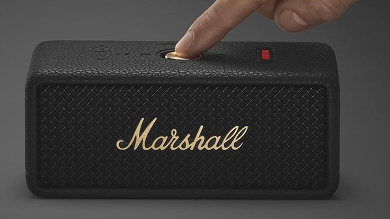 Pressing a button on a black Marshall Emberton III speaker.