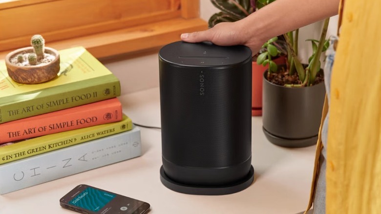 Sonos Move 2 placed on an indoor table alongside books and smartphone.
