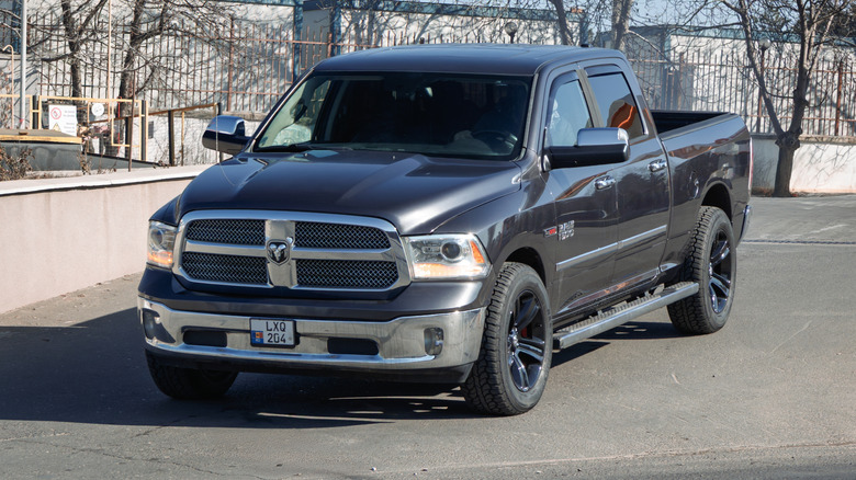 A navy blue and silver fourth-generation RAM 1500 parked at the side of a road.