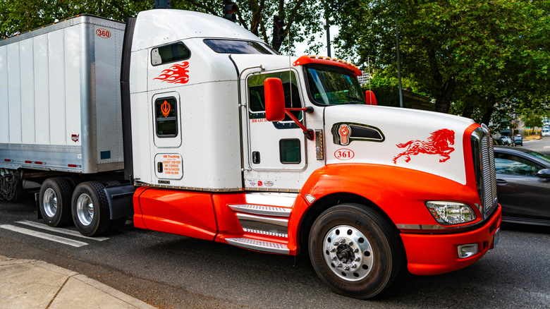 The right-front view of a Kenworth T660 truck in a forested street.