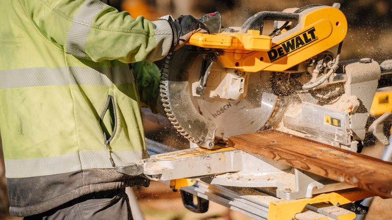person using a DeWalt saw to cut through wood