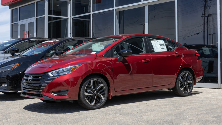 Maroon 2025 Nissan Versa parked in front of a dealership