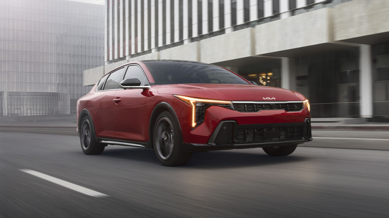 Red 2026 Kia K4 driving in the city