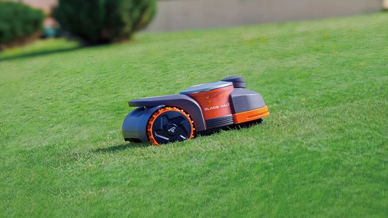 Segway Navimow robotic mower climbing up a hill on a yard.