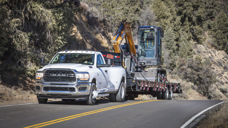 A white 2019 Dodge RAM 3500 with the 6.7 Cummings towing an excavator