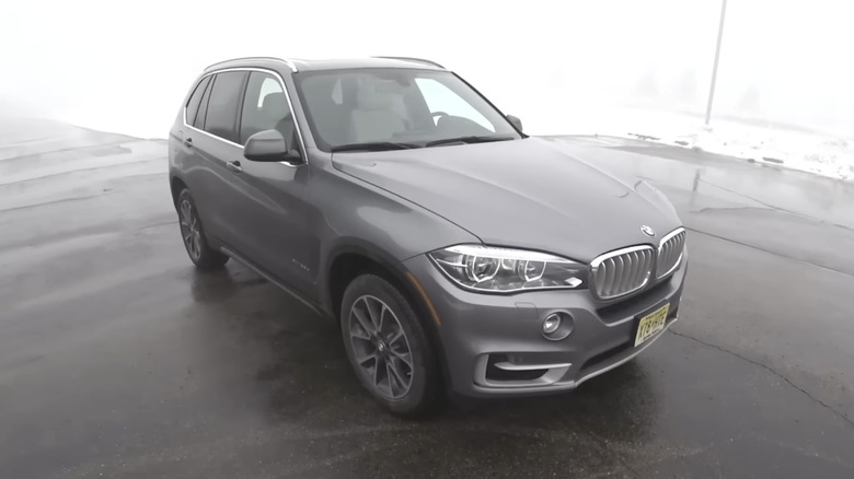 A 2017 BMW X5 parked in a snowy foggy lot