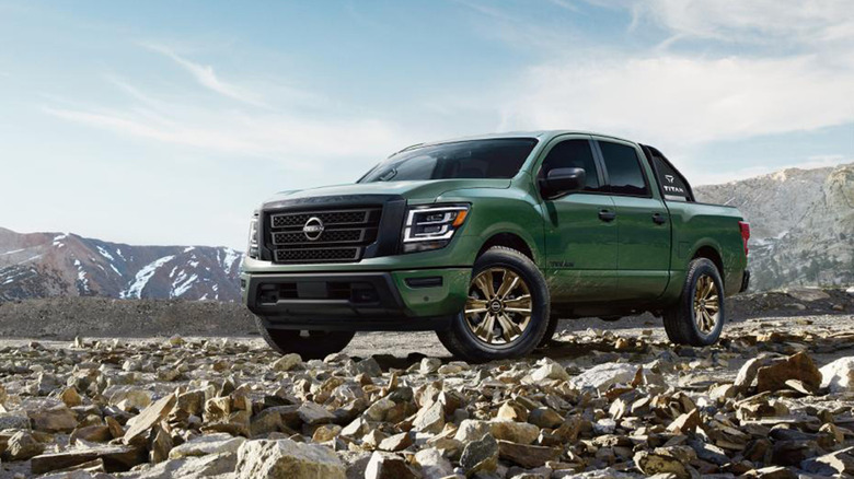 A green Nissan Titan on rocky terrain near a mountain