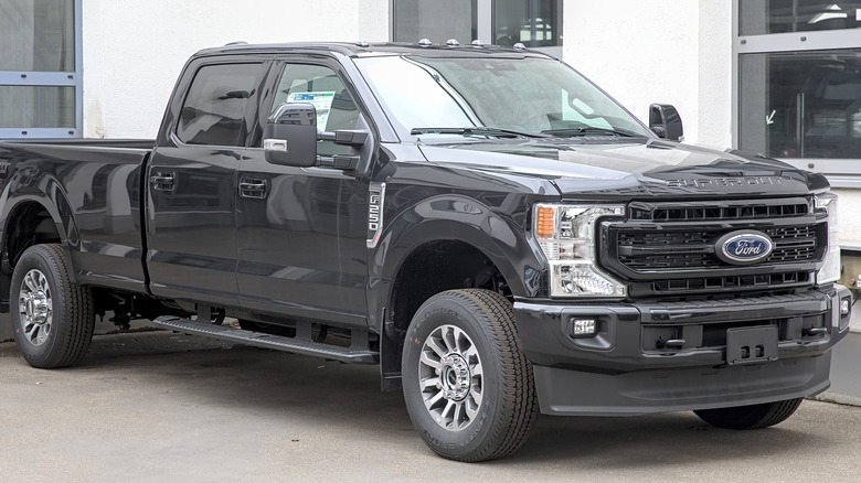 A black Ford F-250 parked in front of a white building.