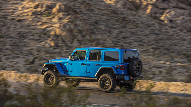 A blue 2020 Jeep Wrangler Rubicon driving on a desert highway.