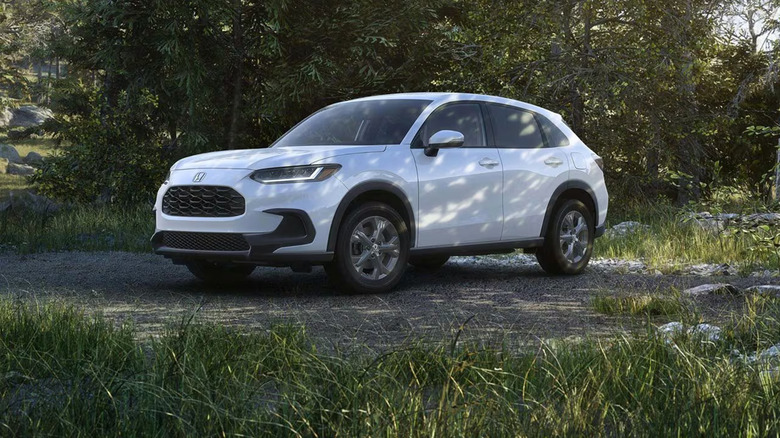 A 2026 model Honda HR-V crossover SUV, finished in white, standing in the shade of several trees.